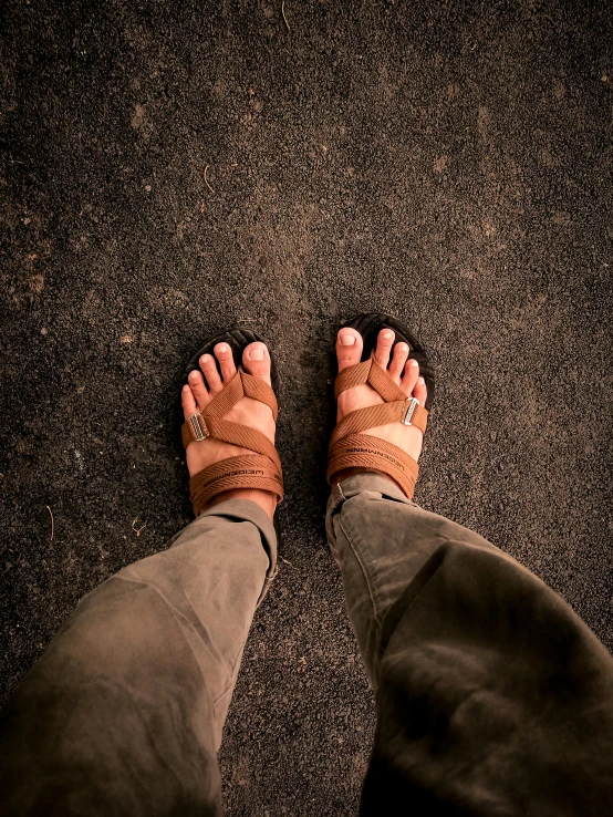 a close up of a person's feet wearing sandals, unsplash, brown clothes, nepal, outside in parking lot, ilustration