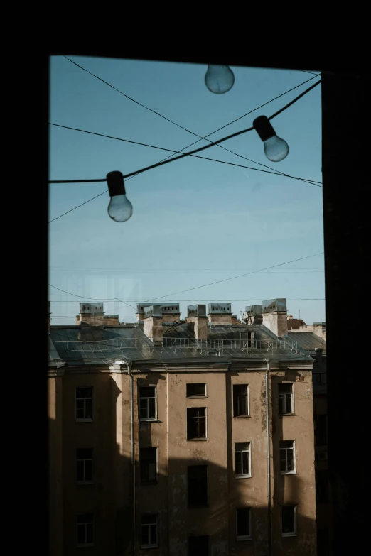 a view of a building through a window, overhead wires, saint petersburg, some bulb lights, afternoon hangout