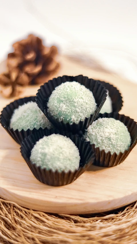 a pile of chocolates sitting on top of a wooden plate, inspired by Kinichiro Ishikawa, hurufiyya, pastel green, festive, cannonballs, thumbnail