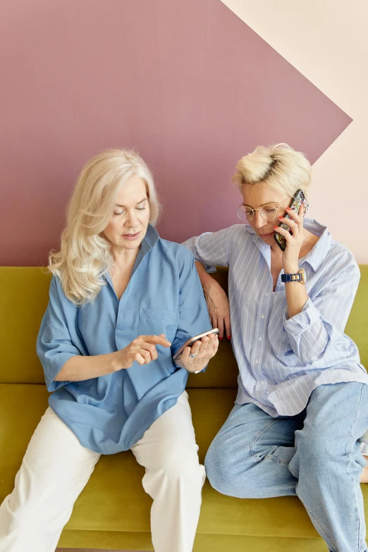 a couple of women sitting on top of a green couch, pexels, happening, white haired lady, phone, digital medical equipment, muted pastels