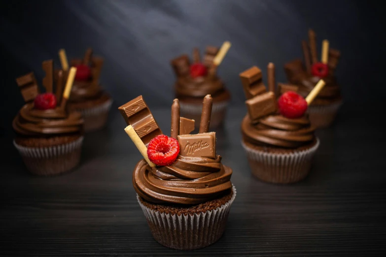 a group of cupcakes with chocolate frosting and raspberries, inspired by Jules Robert Auguste, unsplash, photorealism, twirls, candy treatments, fuji choco