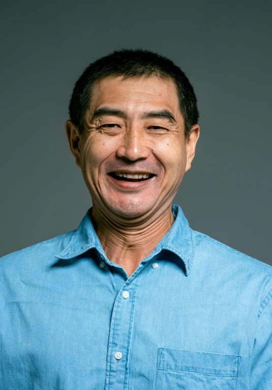 a man in a blue shirt smiling at the camera, inspired by sung choi, on a gray background, ernie chan, middle aged man, gongbi