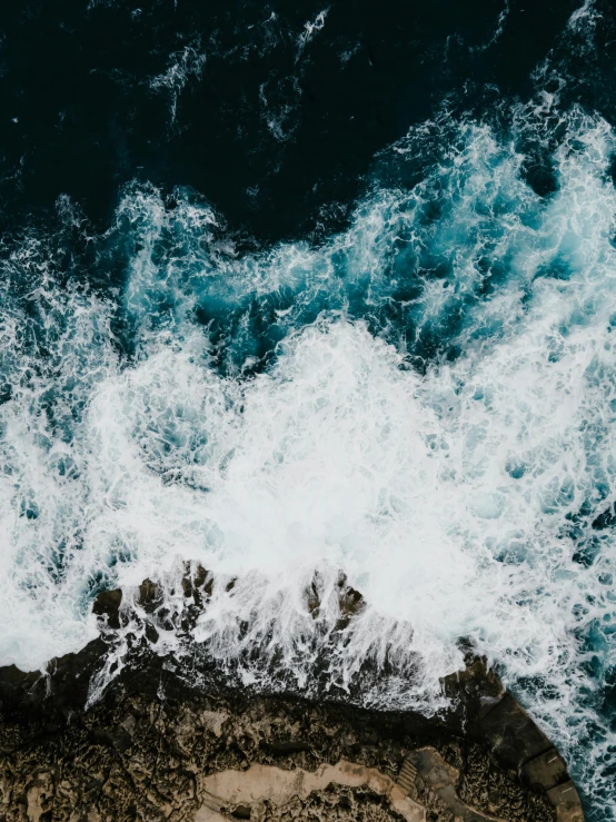 a large body of water next to a rocky shore, pexels contest winner, happening, blue crashing waves, close-up from above, trending on vsco, high - contrast