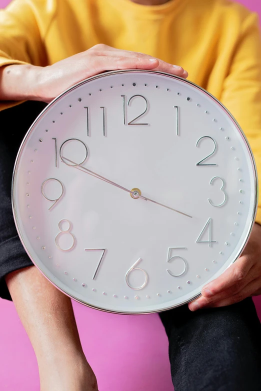 a close up of a person holding a clock, inspired by Peter Alexander Hay, glossy white metal, sitting in a waiting room, thumbnail, teenager