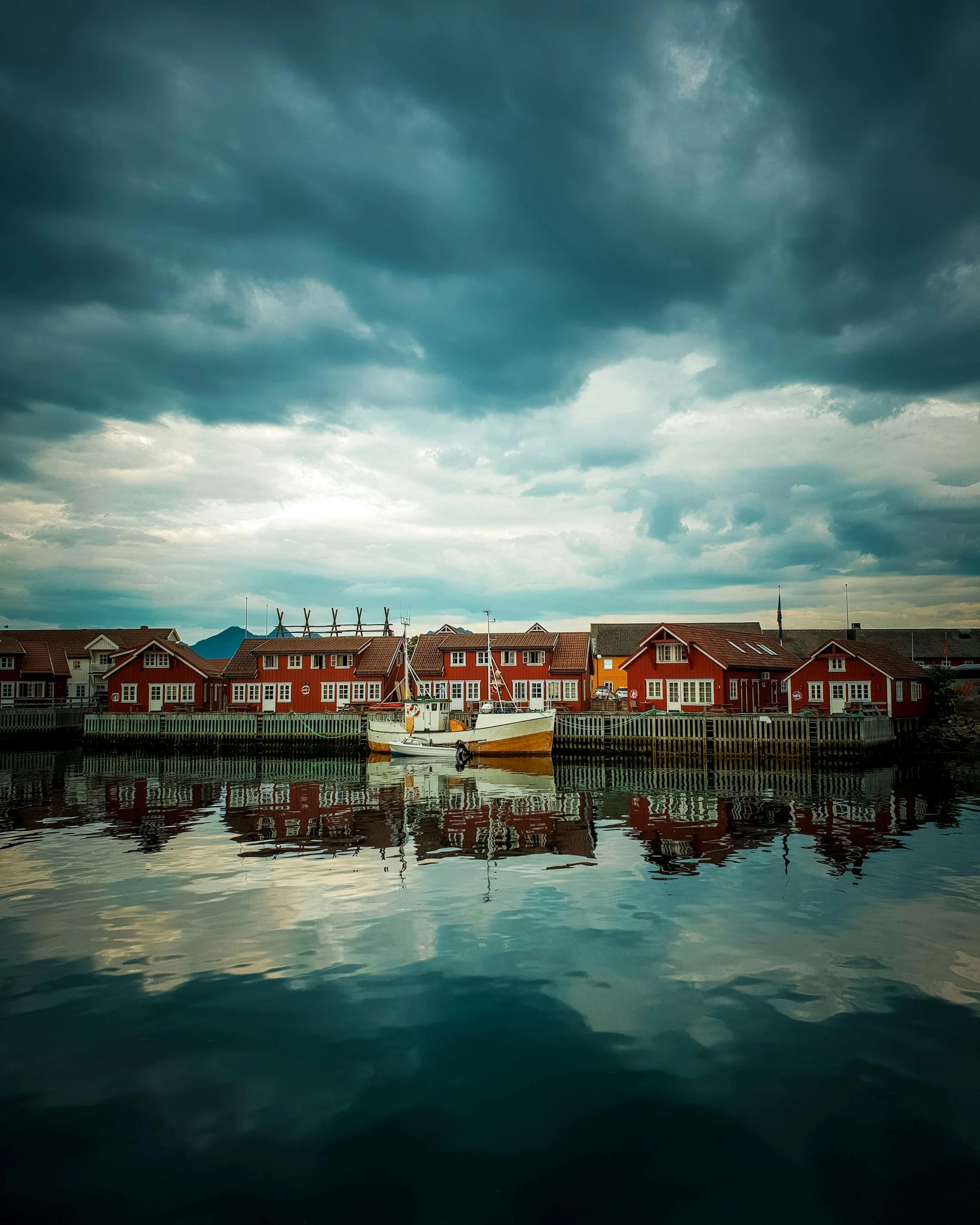 a boat sitting on top of a body of water, by Sebastian Spreng, pexels contest winner, art nouveau, swedish houses, thunderclouds in the sky, docked at harbor, in a row