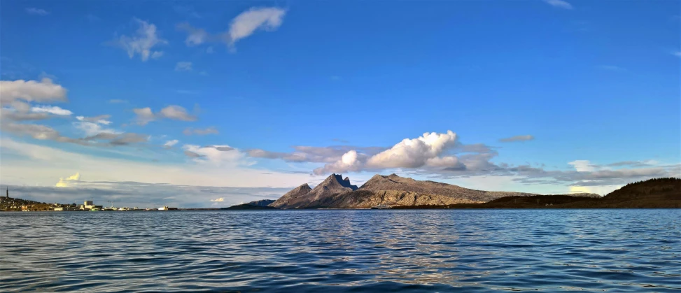 a body of water with a mountain in the background, skye meaker, blue skies, archipelago, gopro photo