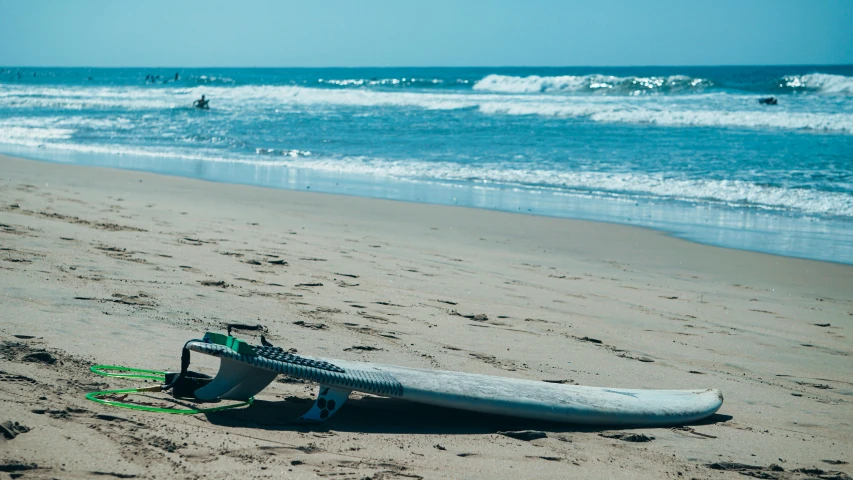 a surfboard sitting on top of a sandy beach, beach on the outer rim