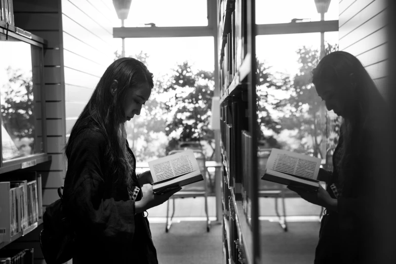 two women are reading books in a library, a black and white photo, by Emma Andijewska, academic art, admiring her own reflection, carson ellis, overlooking, full profile