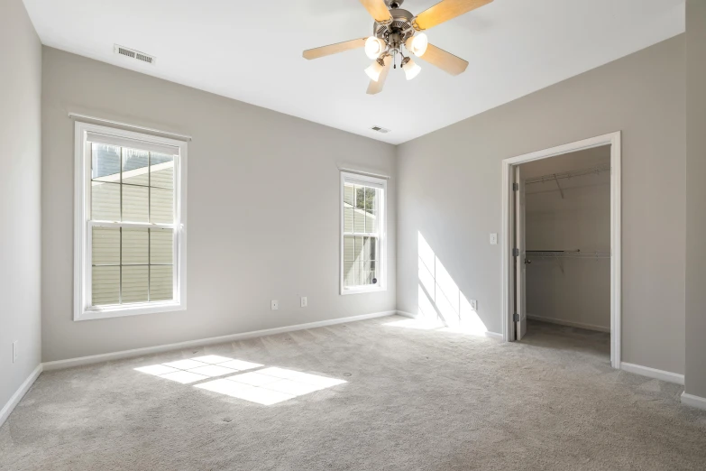 a large empty room with a ceiling fan, by Carey Morris, fan favorite, small bedroom, listing image, large open windows