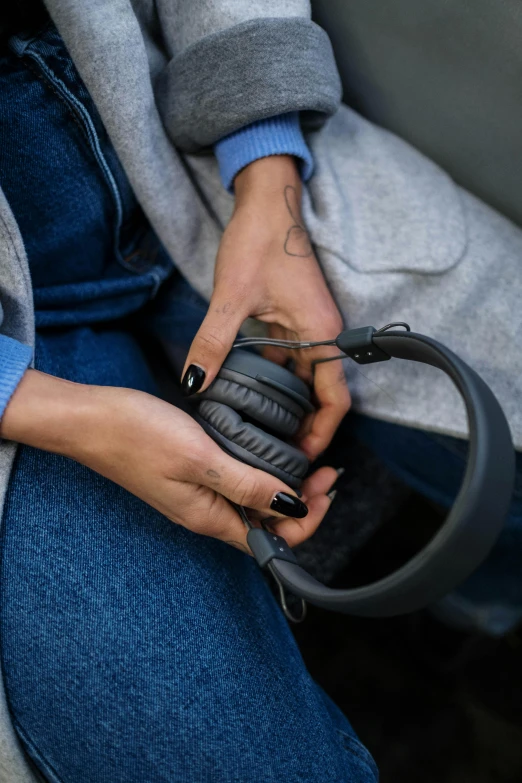 a close up of a person holding a pair of headphones, in gunmetal grey, a pair of ribbed, gadgets, indigo