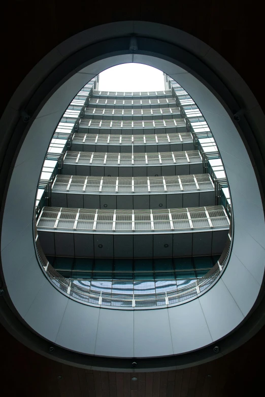 a view of a building through a circular window, inspired by Zaha Hadid, many floors, head looking up, panoramic view, spire