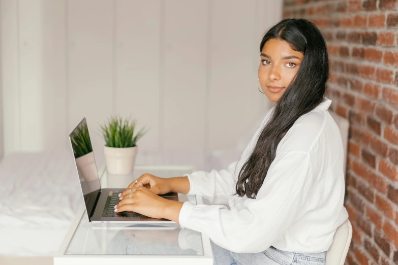 a woman sitting at a desk using a laptop computer, trending on pexels, young himalayan woman, wearing a white blouse, avatar image