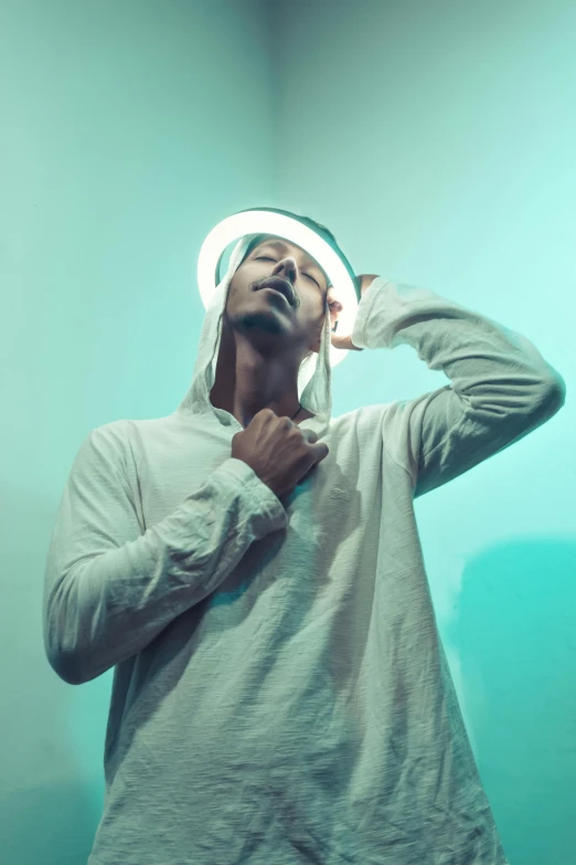 a man standing in a room with a light on his head, inspired by Philipp Veit, pexels contest winner, wearing white silk hood, childish gambino, ring lighting, with hat