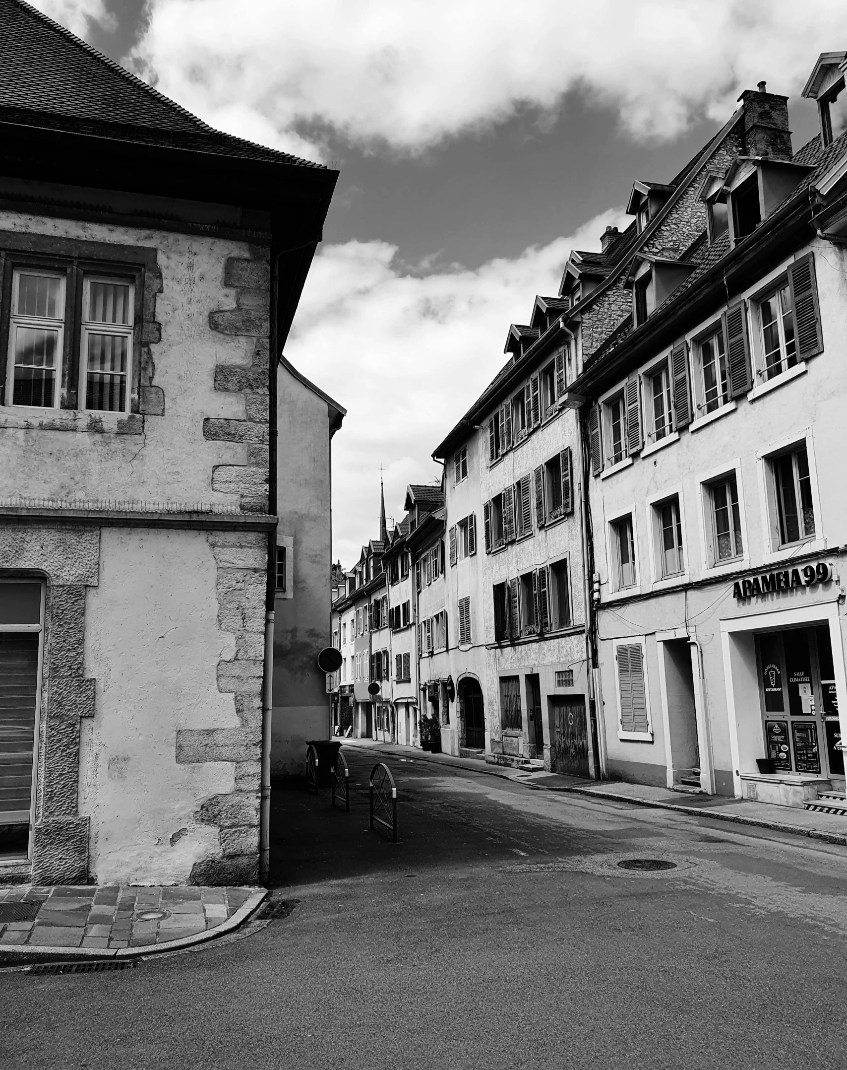 a black and white photo of a narrow street, inspired by Jean Tabaud, pexels contest winner, small town surrounding, swiss architecture, medium format. soft light, village square