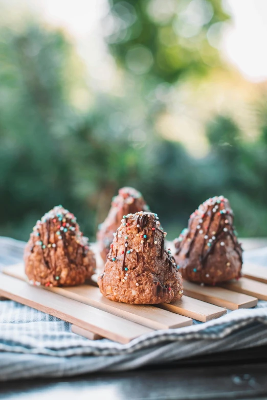 a wooden tray topped with donuts covered in sprinkles, by Jan Tengnagel, unsplash, hurufiyya, cone heads, volcanic, spire, brunettes