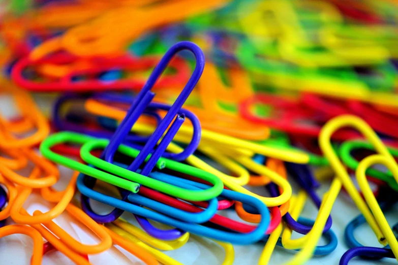 a pile of colorful paper clips sitting on top of a table, by Niko Henrichon, pexels, process art, bright colors highly detailed, deep colour, smooth coloring, day-glo colors