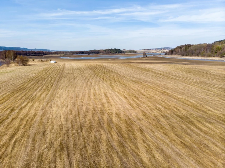 a plowed field with a lake in the background, unsplash, land art, 360 foot wingspan, 2000s photo