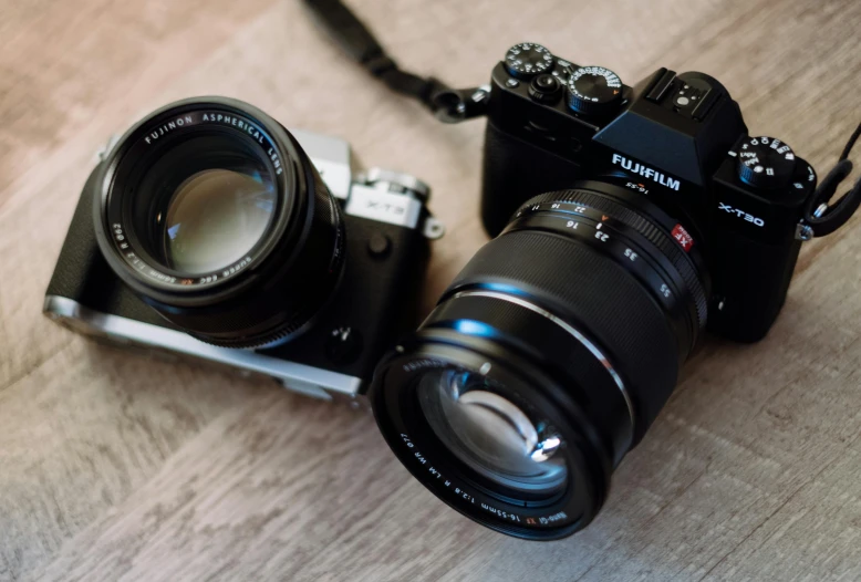 a couple of cameras sitting on top of a wooden table, by Julia Pishtar, fujifilm x - t 4, camera on the ground, crawling towards the camera, picture