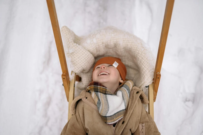 a little boy sitting on a swing in the snow, by Emma Andijewska, pexels contest winner, smiling down from above, brown, sleeping, avatar image