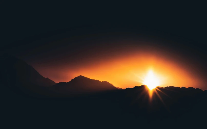 the sun is setting over a mountain range, pexels contest winner, minimalism, explosion of light, on black background, amber glow, post processed