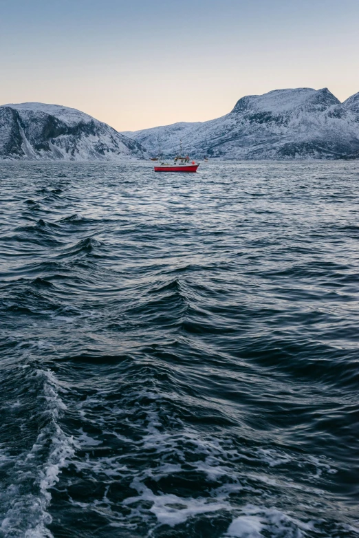 a red boat floating on top of a body of water, a photo, inspired by Johan Christian Dahl, pexels contest winner, cold hues, wavy water, arctic, captured on canon eos r 6