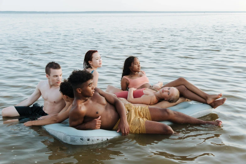 a group of people floating on top of a body of water, by Carey Morris, trending on pexels, with a white complexion, teenager hangout spot, product introduction photo, ignant