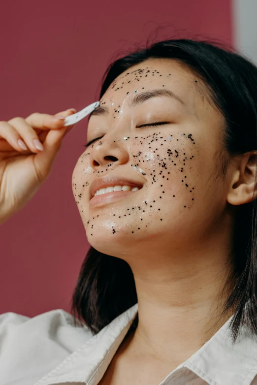 a woman with black spots on her face, trending on pexels, happening, having a good time, her face is coated in a white, asian female, dark glitter