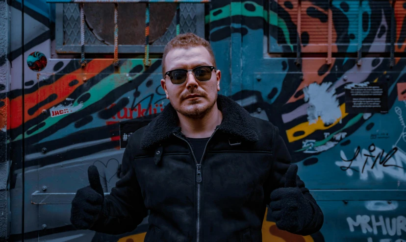 a man standing in front of a graffiti covered wall, an album cover, inspired by Károly Brocky, pexels contest winner, leather clothing, avatar image, shades, profile picture 1024px