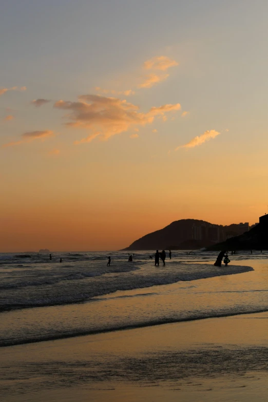 a group of people standing on top of a beach next to the ocean, during a sunset, surfing, kamakura scenery, single file