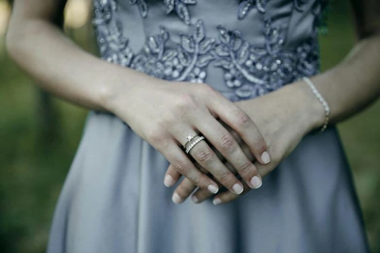 a close up of a person holding a wedding ring, pexels, wearing silver dress, grey and blue theme, wearing a formal dress, her hand is on her waist