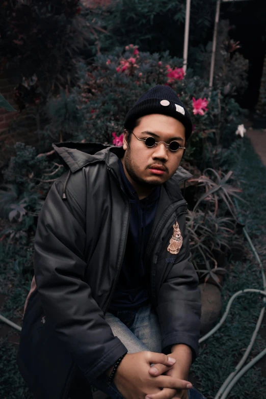 a man in a black jacket sitting on a bench, an album cover, inspired by Eddie Mendoza, unsplash, realism, in a garden, perfectly lit face, big floppa, trending on r/streetwear