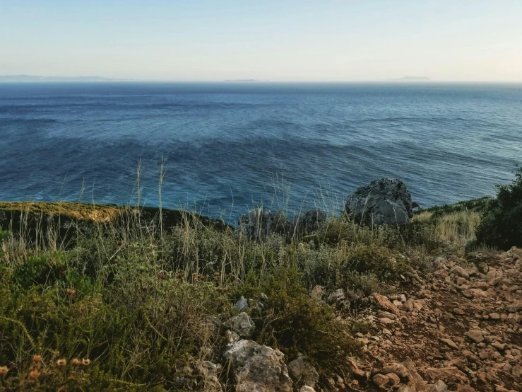 a view of the ocean from the top of a hill, unsplash, les nabis, rocky grass field, mediterranean, conde nast traveler photo