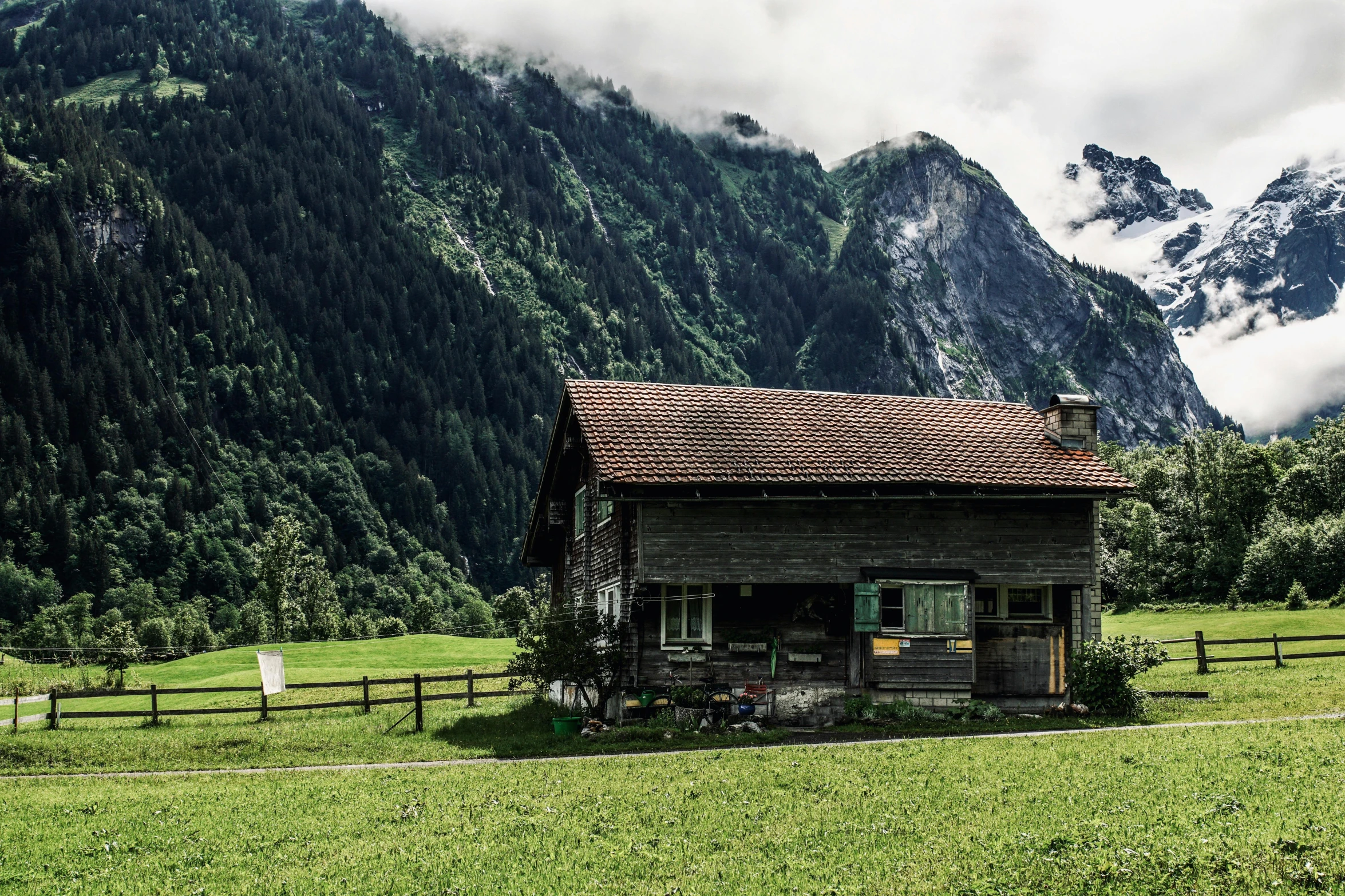 a house in a field with mountains in the background, by Sebastian Spreng, pexels contest winner, chalet, lush green, rustic setting, suzanne engelberg