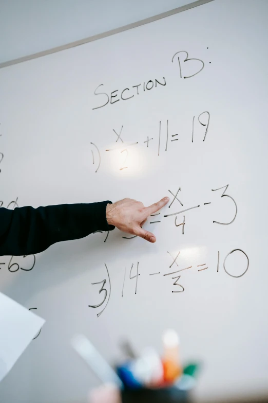 a man standing in front of a whiteboard with writing on it, by Daniel Seghers, pexels, algebra, hand gesture, paul barson, 15081959 21121991 01012000 4k