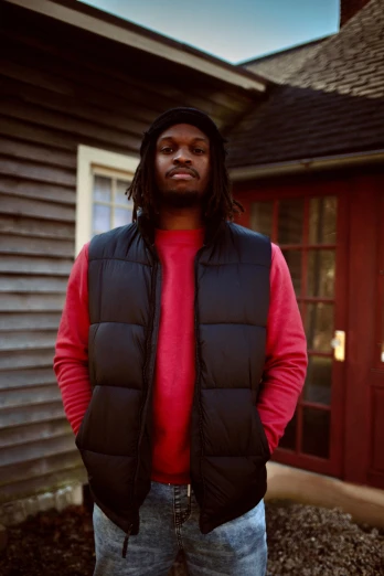 a man standing in front of a house, an album cover, by Stokely Webster, unsplash, renaissance, wearing a red gilet, headshot, ap, thicc