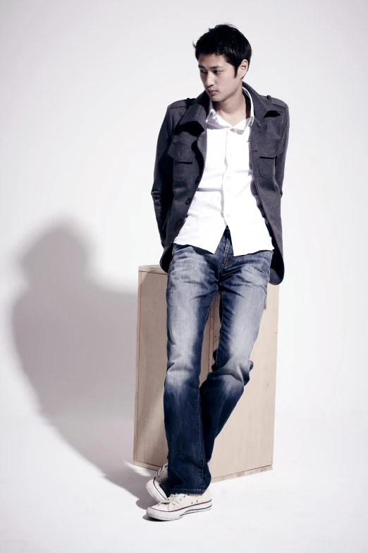 a man sitting on top of a wooden box, inspired by derek zabrocki, wearing jeans, white backdrop, ryuichi sakamoto, smart casual