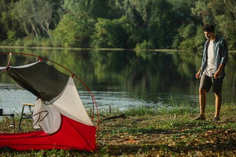 a man standing next to a tent next to a lake, by Joe Stefanelli, pexels contest winner, hurufiyya, bayou, red river, avatar image, panoramic shot