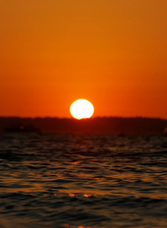 the sun is setting over a body of water, zoomed out photography, orange, medium-shot, f/3.2