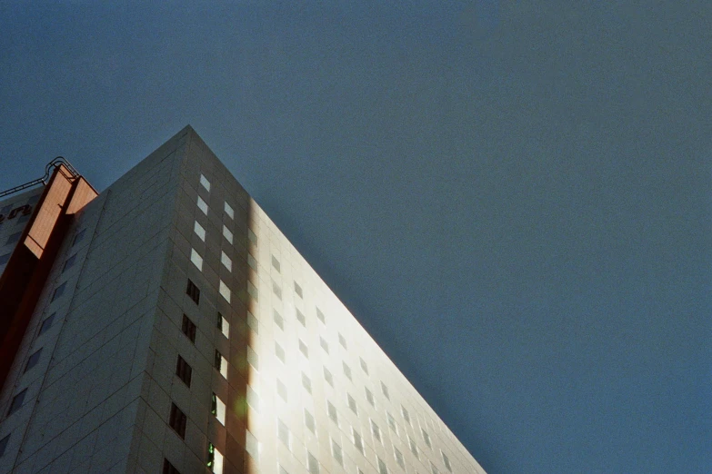 a tall building sitting in the middle of a city, an album cover, inspired by Richard Wilson, unsplash, light and space, shot on superia 400 film stock, ignant, 50mm photograph, front lit