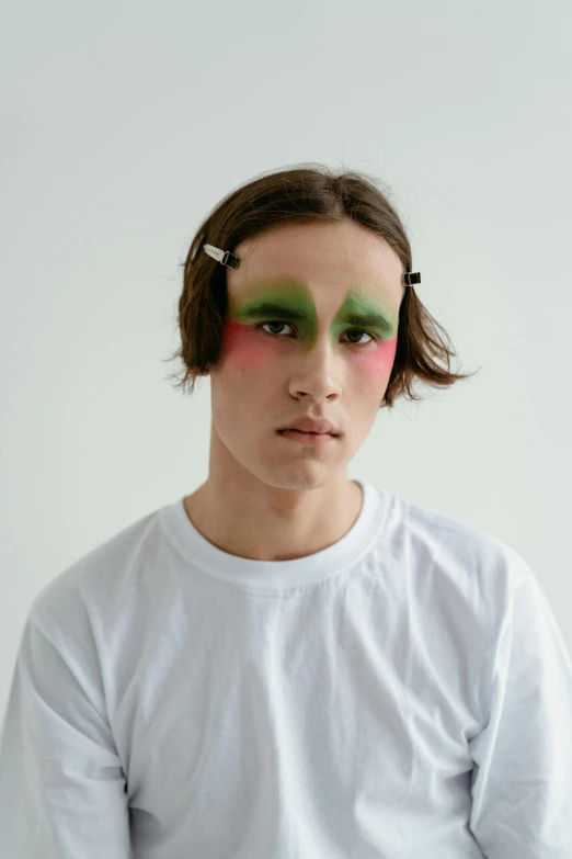 a close up of a person wearing a white shirt, an album cover, inspired by Russell Dongjun Lu, wearing war paint, green and red tones, teen boy, large bushy eyebrows