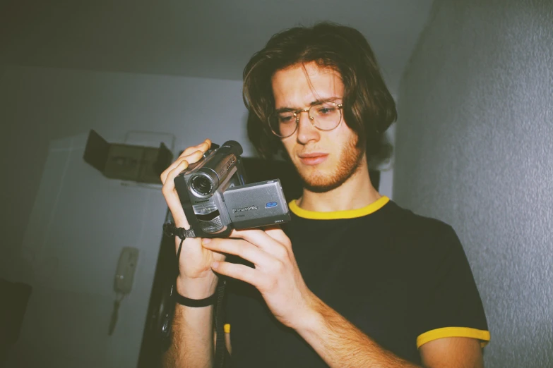 a close up of a person holding a camera, 9 0 s vhs aesthethic, liam brazier, lovingly looking at camera, in an action pose