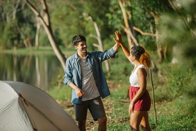 a man and a woman standing next to a tent, pexels contest winner, waving arms, sydney park, on a riverbank, flirting