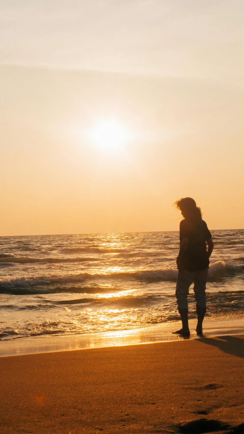 a person standing on a beach at sunset, pexels, teenage girl, sunny amber morning light, with a long, idyllic