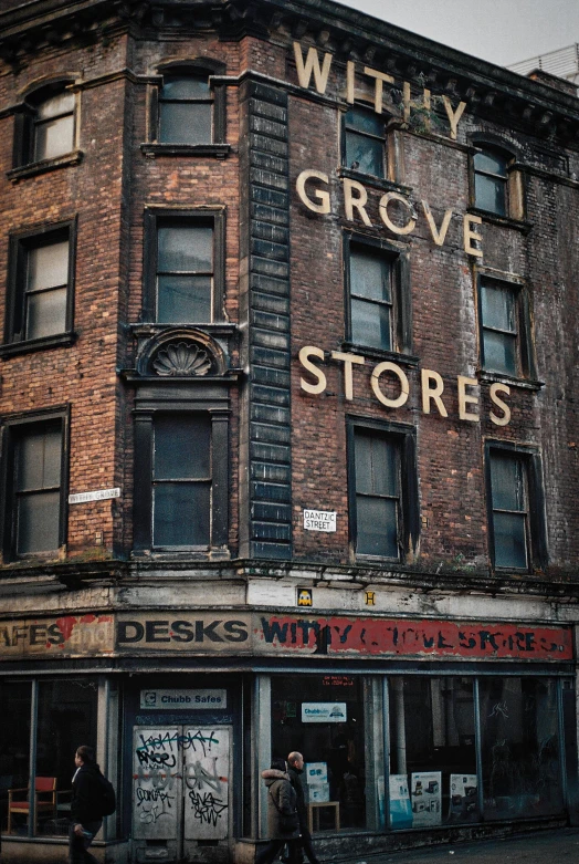 a tall brick building sitting on the side of a street, an album cover, inspired by William Gropper, pexels contest winner, graffiti, gravestones, sitting on a store shelf, glasgow, groovival aesthetic