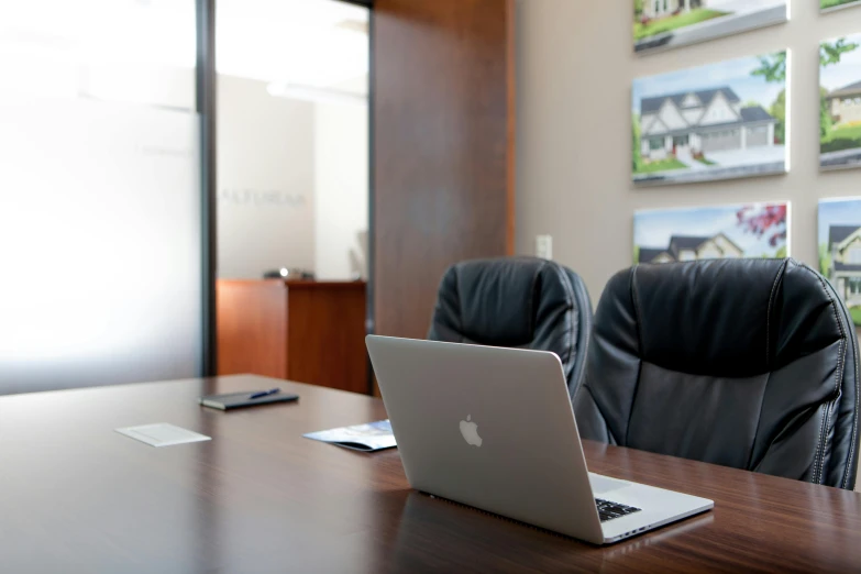 a laptop computer sitting on top of a wooden table, a photo, by Gavin Nolan, hurufiyya, office interior, vaughan ling, in a meeting room, alexandre bourlet