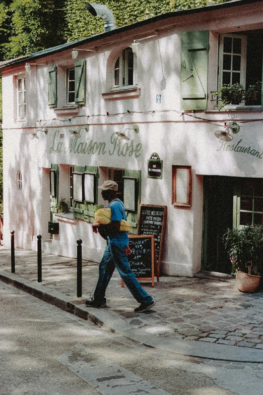 a group of people walking down a street next to a building, an album cover, inspired by Maurice Utrillo, trending on unsplash, paris school, 35mm film still from 1994, lush surroundings, restaurant, man standing