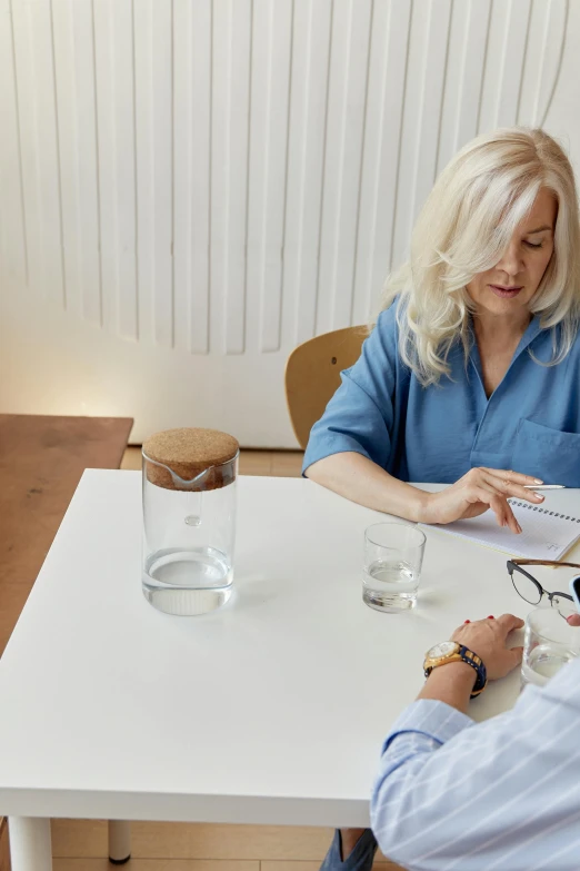 a man and a woman sitting at a table, product design shot, hydration, jenni pasanen, writing on a clipboard