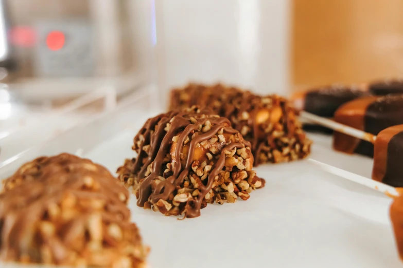 a number of desserts on a plate on a table, by Emma Andijewska, pexels, hurufiyya, rocky roads, close-up shot from behind, chocolate candy bar packaging, made of glazed