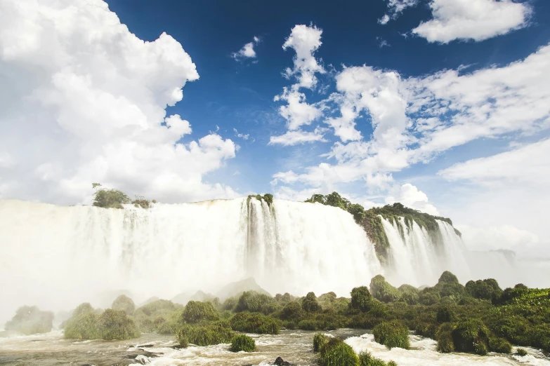 a large waterfall in the middle of a lush green forest, an album cover, pexels contest winner, hurufiyya, buenos aires, blue skies, national geographics, historical setting