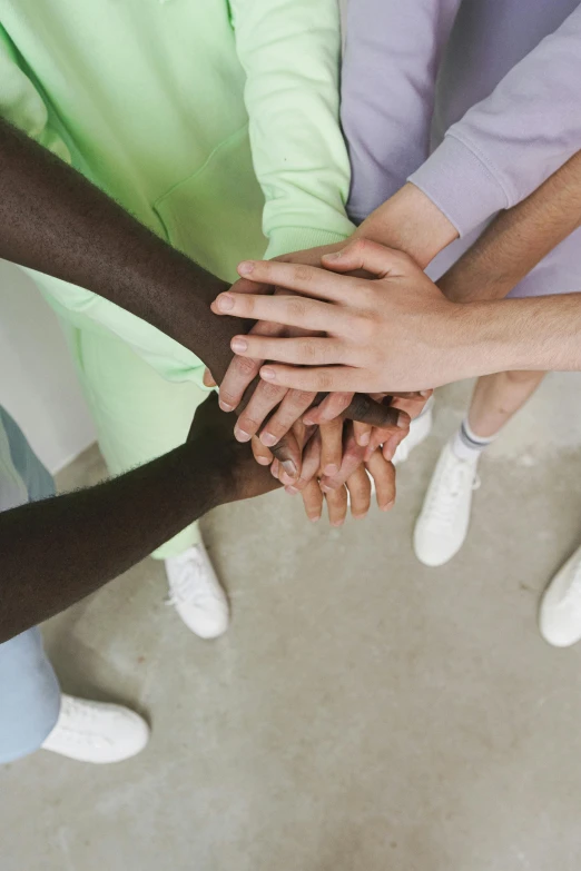 a group of people putting their hands together, by Nina Hamnett, healthcare worker, color photograph, diverse colors, gray men